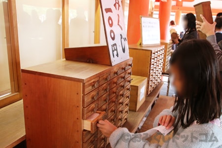 厳島神社 おみくじを棚引き出しから出している様子